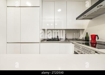 Cuisine meublée dans un appartement loft avec mobilier blanc avec pierre grise Banque D'Images