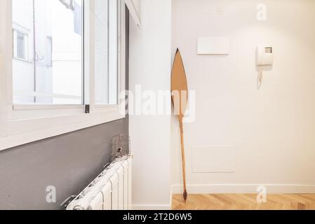 Hall et couloir d'un appartement résidentiel avec parquet en chêne, fenêtre sur le patio intérieur et murs peints en blanc lisse Banque D'Images