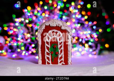 Maison en pain d'épice au-dessus des lumières de sapin de Noël défocalisées. Banque D'Images