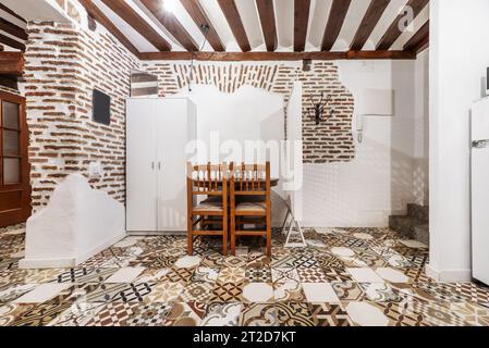 Chambre dans un ancien appartement orné de style champêtre avec murs en briques apparentes, poutres apparentes et carreaux de ciment assortis Banque D'Images