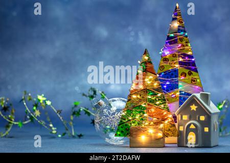 arbres de noël décorés par des lumières brillantes de vacances avec des ornements de nouvel an sur fond bleu flou. Banque D'Images