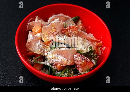 jambon de parme et mélange de feuilles salade en fond noir Banque D'Images
