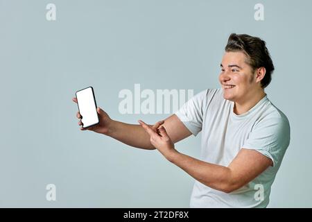 Un homme à bout de bras montre un écran de téléphone sur fond gris, maquette Banque D'Images