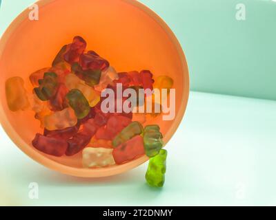 les ours gommeux de différentes couleurs se trouvent en plastique et en forme ronde rose. les ours en peluche sont empilés dans la cuisine dans un arroseur de cuisine. bonbons sur un mat c Banque D'Images