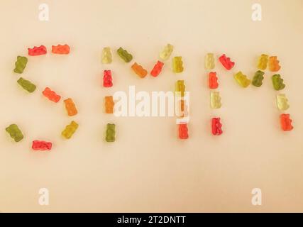 lettre d'ours gommeux multicolores. Lettres S et M faites de bonbons gélatineux sur fond orange mat. Mot comestible SMM. commercialisation des gommes Banque D'Images