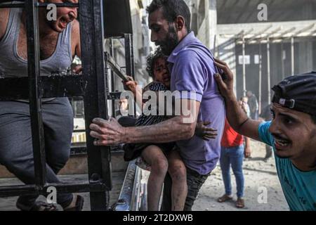 Un père palestinien tente d’évacuer une famille, dont la plupart ont été blessées lors d’une frappe aérienne israélienne sur le quartier d’Al-Zaytoun, à l’est de la ville de Gaza. Palestine. Banque D'Images