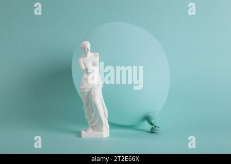 Une Vénus de Milo devant un ballon turquoise de la même couleur que le fond. Monochrome et nuances de couleur. Contraste entre une sculpture classique Banque D'Images