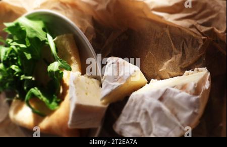 Camembert et crêpe sur papier parchemin et planche de bois Banque D'Images