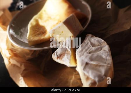 Camembert et crêpe sur papier parchemin et planche de bois Banque D'Images