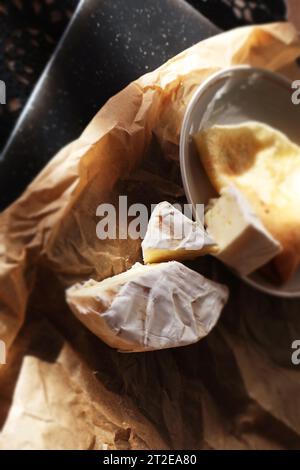 Camembert et crêpe sur papier parchemin et planche de bois Banque D'Images