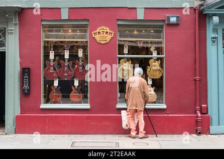 Un homme âgé avec un bâton de marche faisant du shopping à la fenêtre au no. Tom Guitars, Denmark Street, Londres, WC2, Angleterre, ROYAUME-UNI Banque D'Images