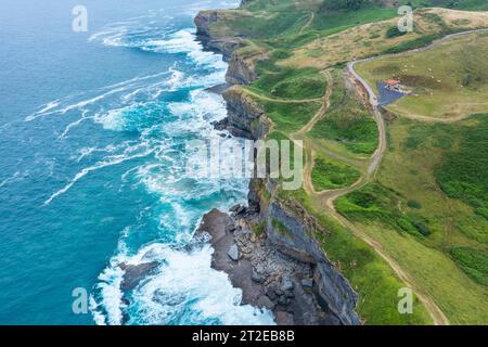 Vue aérienne d'un paysage côtier avec falaises rocheuses et prairies verdoyantes. Cantabrie, Espagne. Banque D'Images