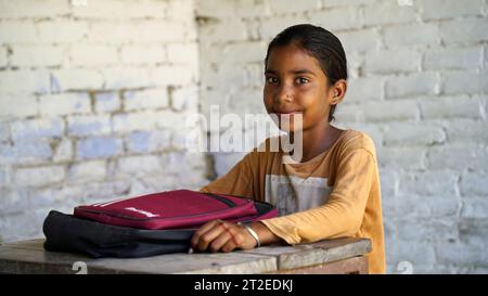 Heureux élèves de filles d'école primaire indienne assis au bureau dans la salle de classe avec l'écriture dans le cahier avec crayon, examen et test, éducation féminine Banque D'Images