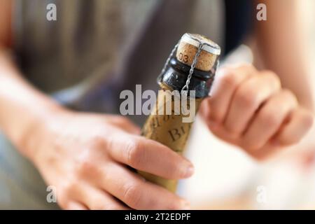 Mains, personne et bouchon ouvert sur bouteille de vin, champagne et alcool pour la fête, la célébration et félicitations pour l'événement spécial. Gros plan, boire et Banque D'Images