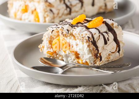Dessert suédois traditionnel sans gluten rouleau Budapest rempli de crème fouettée et de mandarines en gros plan dans une assiette sur la table. Horizontal Banque D'Images