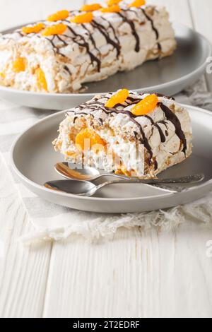 Gâteau roulé Budapest classique sans gluten avec mandarines closeup sur l'assiette sur la table. Vertical Banque D'Images