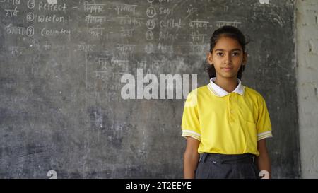 Portrait de l'enfant heureux de l'école indienne assis au bureau dans la salle de classe, les enfants de l'école avec des stylos et des cahiers test d'écriture École élémentaire, éducation conc Banque D'Images