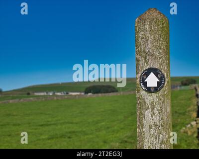 Un marqueur noir et blanc sur un poteau en bois patiné indique le chemin sur une route à travers le Peak District dans le Derbyshire, au Royaume-Uni. Pris sur une journée ensoleillée wi Banque D'Images