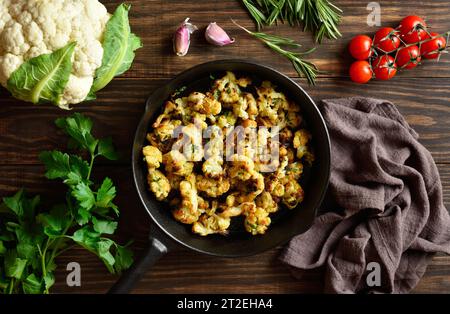 Chou-fleur rôti dans une poêle en fonte sur une table en bois. Vue de dessus, pose à plat Banque D'Images