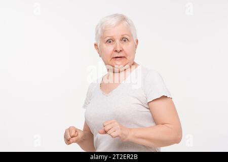 Femme caucasienne âgée senior exprimant choquée et la peur se sentant en studio tourné dans un fond blanc isolé Banque D'Images