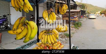 Gros plan d'un bouquet de bananes jaunes mûres accrochées à un poteau sur un marché Banque D'Images