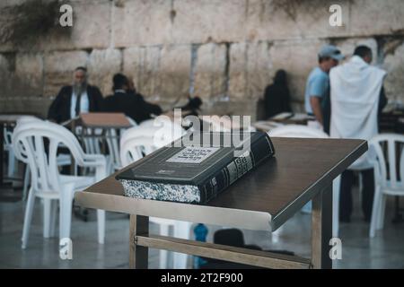 Gros plan du Saint livre juif fermé Torah, laissé sur la table avec les juifs ultra-orthodoxes au mur des lamentations en arrière-plan. Livre avec l'écriture hébraïque Banque D'Images