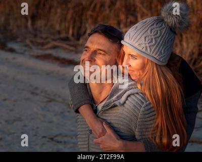 Couple intime embrassant, portant des vêtements d'hiver et chapeau de Bobble dans la nature, vue optimiste vers l'horizon, confiance dans la création de Dieu, l'Allemagne Banque D'Images