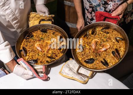 Deux cuisiniers avec des paellas de fruits de mer, cuisine méditerranéenne traditionnelle espagnole. Riz aux moules, crevettes et calmars Banque D'Images