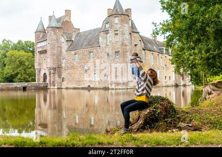 Une jeune mère avec son bébé visitant le Château médiéval Trecesson au bord du lac, commune de Campeneac dans le département du Morbihan, près de la Banque D'Images