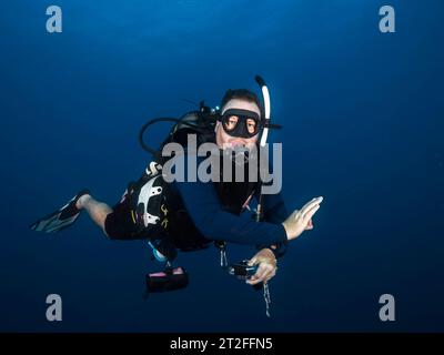 Gros plan d'un plongeur masculin dans la mer bleu profond regardant la caméra montrant le signal ok Banque D'Images