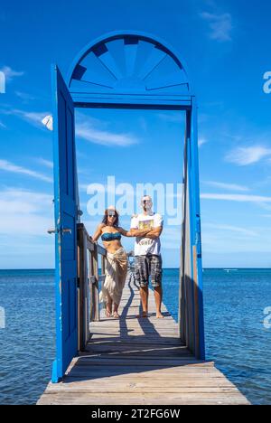 Un couple à une porte bleue sur la plage de Sandy Bay sur l'île de Roatan. Honduras Banque D'Images