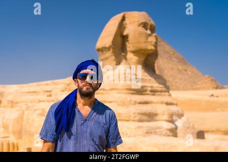 Portrait d'un jeune touriste vêtu de bleu et d'un turban bleu au Grand Sphinx de Gizeh. Le Caire, Égypte Banque D'Images