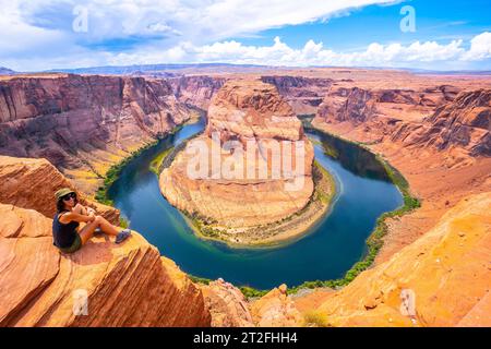 Un touriste assis sur Horseshoe Bend et le fleuve Colorado en arrière-plan, Arizona Banque D'Images