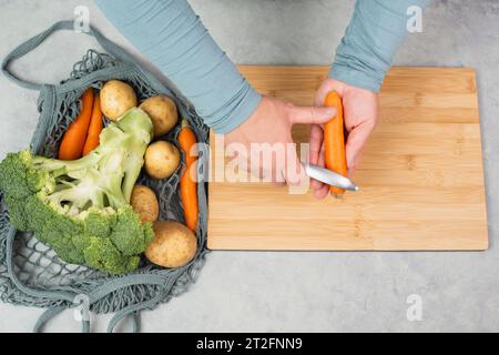 Épluchez la carotte avec un affûteur grattoir, préparez des aliments sains avec des légumes, une nutrition biologique fraîche, des ingrédients de cuisine Banque D'Images