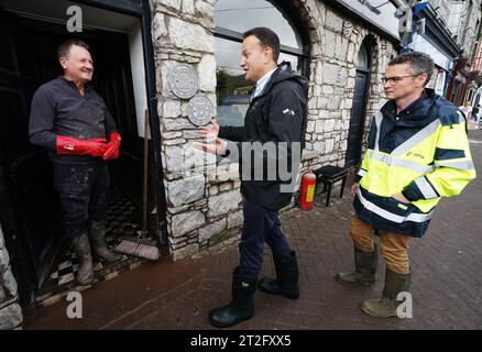 Le Taoiseach Leo Varadkar (au centre) et Patrick O'Donovan (à droite), ministre d'État chargé du Bureau des travaux publics, sont accueillis par Pat O'Donovan (à gauche), propriétaire du restaurant O'Donovan sur main Street à Midleton, Co Cork, à la suite des dégâts considérables causés par la tempête Babet, la deuxième tempête nommée de la saison. Date de la photo : jeudi 19 octobre 2023. Banque D'Images