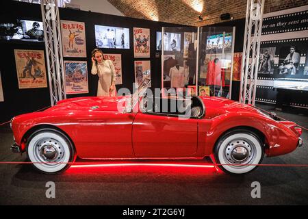 Londres, Royaume-Uni. 19 octobre 2023. Un visiteur pose avec la MGA 1600 MKI 1960 d'Elvis, la seule voiture personnelle d'Elvis qui a fini dans l'un de ses films, utilisé dans le film de 1961 'Blue Hawaii'. L'exposition « Direct from Graceland : Elvis » présente plus de 400 objets et objets emblématiques appartenant à Elvis, directement depuis la maison de l'icône Graceland à Memphis, Tennessee. L'exposition ouvre le 20 octobre au Arches London Bridge, à Bermondsey Street. Crédit : Imageplotter/Alamy Live News Banque D'Images