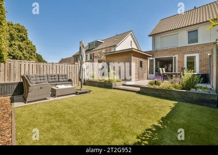 une arrière-cour avec pelouse, canapé et clôturé dans la cour arrière sur une photo stock de jour de ciel bleu clair Banque D'Images