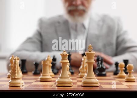 Pièces d'échecs sur échiquier, mise au point sélective. Homme participant à un tournoi en salle Banque D'Images