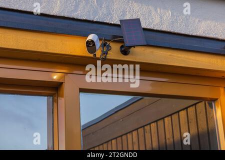 Vue de la caméra de sécurité extérieure high-tech équipée d'un panneau solaire monté sur la façade de la maison. Suède. Banque D'Images