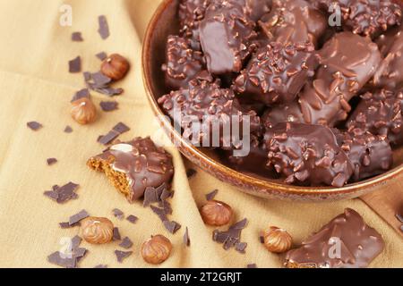 Chocolat avec noisettes dans un bol en céramique sur le fond de tissu brun. Banque D'Images