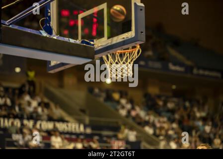 image floue d'un basket s'approchant du cerceau dans l'air au premier plan le panier et les stands en arrière-plan avec le public. Banque D'Images