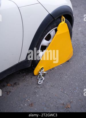 Une voiture dans la rue avec Une pince (ou botte Denver) sur sa roue après avoir été garée illégalement (avec Copy Space) Banque D'Images