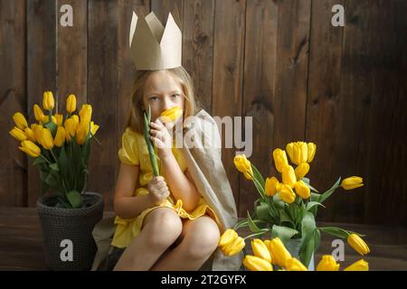 Portrait d'une princesse qui est assise à côté de bouquets de tulipes jaunes. Sentir une fleur. Cadre horizontal. Banque D'Images