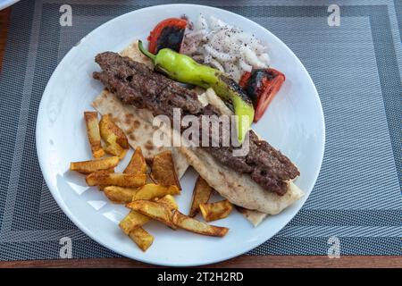 Turc Urfa kebab. Kebab avec pain de laves, pommes de terre et salade. Photo prise à Side, Turquie. Banque D'Images