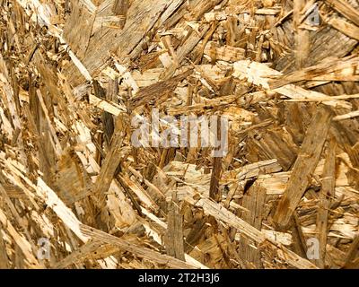 Textures d'un angle de matériaux de construction jaune en bois à partir de copeaux et de sciure comprimée OSB, déchets de production de meubles. L'arrière-plan. Banque D'Images