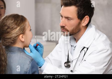 Médecin prélevant un échantillon d'écouvillon de gorge de la cavité buccale de la fille à l'intérieur Banque D'Images