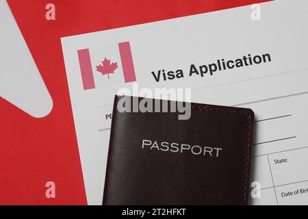 Immigration au Canada. Formulaire de demande de visa et passeport sur drapeau, pose à plat Banque D'Images