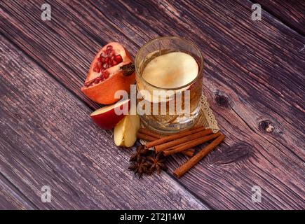Cidre de grenade de pomme, alcool maison fort dans un verre de cristal sur une table en bois sombre, à côté de bâtonnets de cannelle et d'anis. Vue de dessus, pose à plat. Banque D'Images