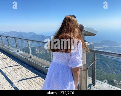 Les mains des femmes tiennent le télescope touristique. Vue depuis la terrasse d'observation (plate-forme d'observation) sur le paysage des montagnes. Promenade touristique, excursions Banque D'Images