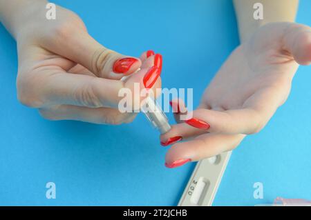 Médecin dans des gants de protection touchant la goutte de sang sur la main du patient avec la lame d'échantillon. Banque D'Images